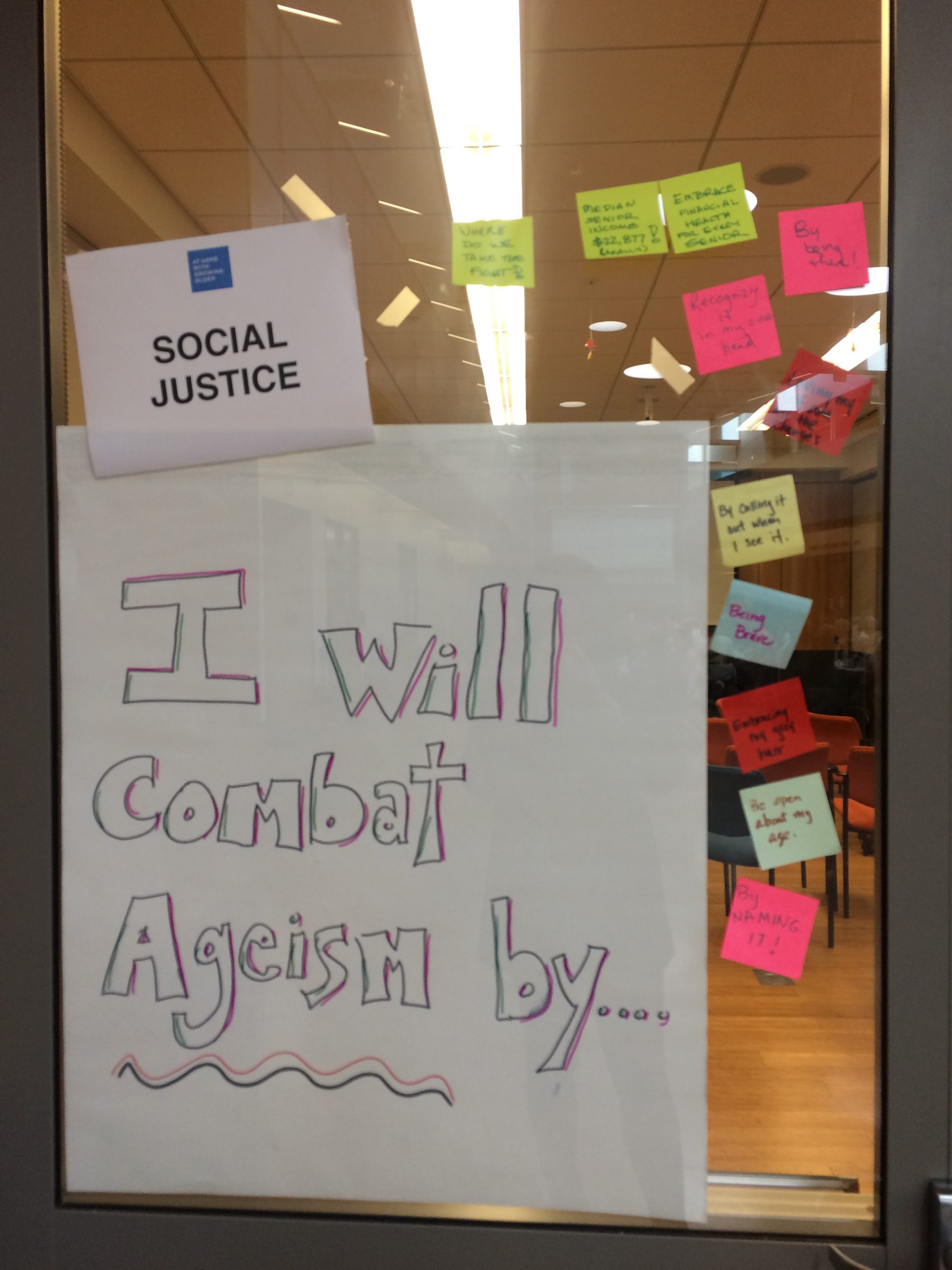 Interactive activity titled “I will combat ageism by…” written on poster paper. Participants provided sticky notes finishing the sentence.