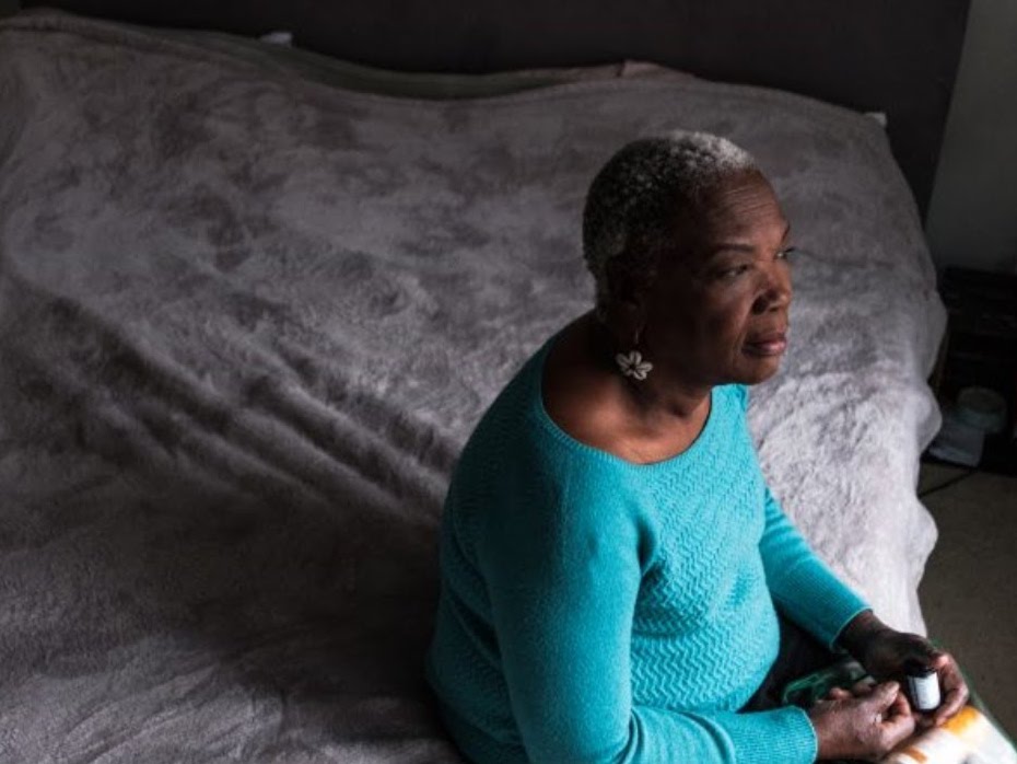 A woman sitting on a bed and looking out the window.